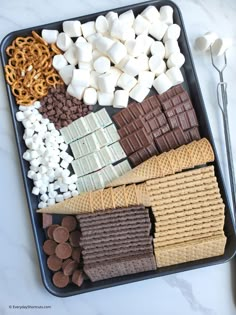 a tray filled with marshmallows, pretzels and chocolate