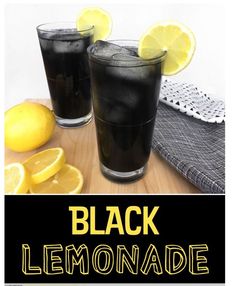 two glasses filled with black lemonade sitting on top of a wooden table next to sliced lemons