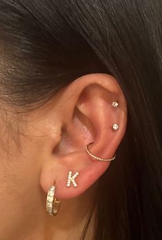 a close up of a person wearing ear piercings with the letter k on it