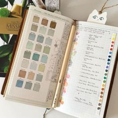 an open planner book with lots of color swatches on it and a cat ornament hanging from the top