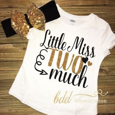 a white shirt that says little miss and two much with gold glitter bows on it