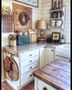 a kitchen with white cabinets and lots of items on the counter top in front of it