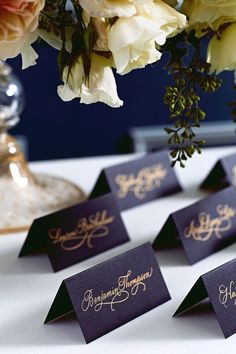 there are place cards on the table with flowers