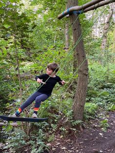 a young boy is zipping through the trees on a rope course in the woods