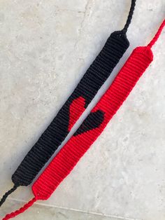 two red and black crocheted lanyards sitting on top of a white surface