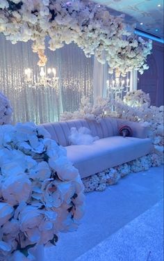 a couch with flowers on it in front of a white curtain and chandelier