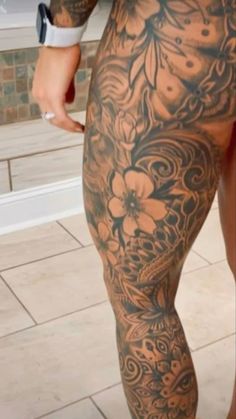 a man with tattoos on his legs and leggings is standing in front of a tiled floor