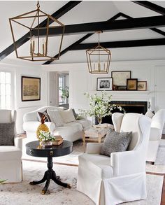 a living room filled with white furniture and lots of pictures hanging on the wall above it