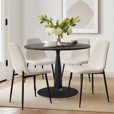 a dining room table with four chairs around it and a vase on top of the table