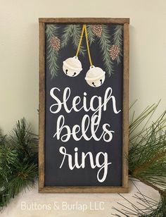 a sign that says sleigh bells ring with pine cones hanging from the top