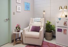 a white chair sitting next to a refrigerator in a room with pictures on the wall