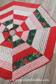 a red and white quilted table topper on a wooden floor with a circular hole in the center