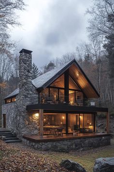 a stone and wood cabin in the woods with lights on it's windows at night