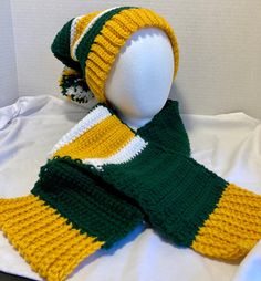 a knitted scarf and hat on a mannequin's head, both in green and yellow