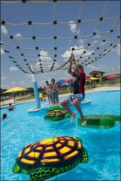 a young boy jumping into a swimming pool with two turtles on the bottom of it