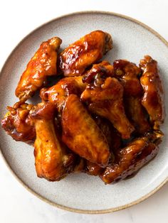 a white plate topped with chicken wings covered in sauce