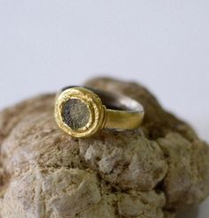 "A circular piece of ancient roman glass is set in a 24k gold bezel on a wide sterling silver band. This ancient roman glass silver and gold ring would make a unique engagement ring or wedding band, or a great everyday ring. The wide 5mm silver band has a comfort fit profile (oval on the inside and round on the outside), making it very comfortable. The band itself is wrapped in 24k gold giving it the appearance of a gold ring. On both sides of the ring is a 22k gold wire, adding a small yet love Silver And Gold Ring, Roman Glass Jewelry, Ancient Roman Glass, Persian Turquoise, 24 Karat Gold, Everyday Ring, Glass Ring, Roman Glass, Handmade Fine Jewelry