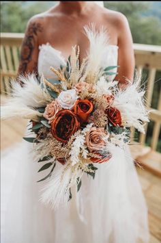 a bride holding a bouquet of flowers and feathers