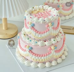 three tiered cake sitting on top of a white table next to a wooden lamp