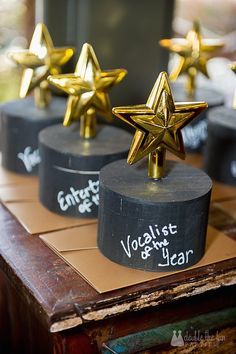 three gold stars sitting on top of a wooden table next to each other with writing on them