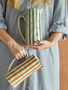 a woman holding a striped coffee mug in her hands