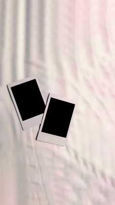 two black and white square pictures are laying on a bed sheet, with the background blurry