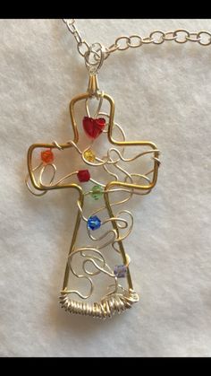 a cross that has been made out of wire and glass beads with hearts on it