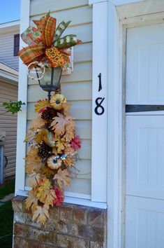 a fall wreath hanging on the side of a house with an address sign and number