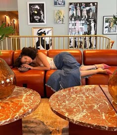 a woman laying on top of a couch in a living room next to two tables