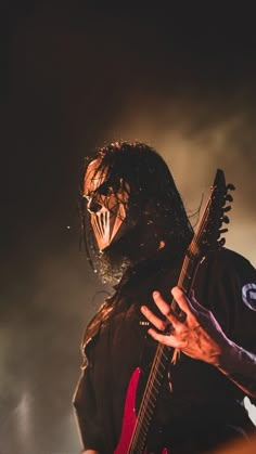 a man with long hair holding a guitar