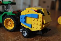 two lego vehicles sitting on top of a wooden table next to each other, one yellow and the other green