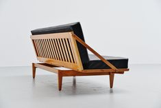 a wooden chair with black leather seat and arm rest on white floored room surface