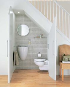 an open door leading to a bathroom with a toilet and sink under the stair case