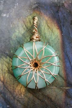 a wire wrapped pendant with a green glass bead hanging from it's end