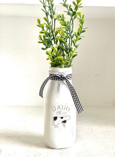 a white vase with some green plants in it