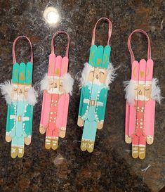 three wooden peg dolls are sitting on a counter top, one is pink and the other is blue