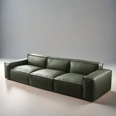 a green leather couch sitting on top of a white floor next to a gray wall