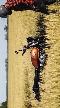 an orange and black motorcycle parked in the grass