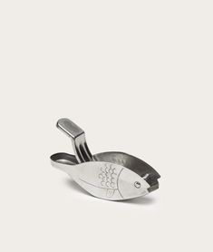 a silver fish shaped dish with tongs in the shape of a fish on it's side