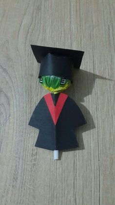 an origami graduation cap and gown on top of a wooden table