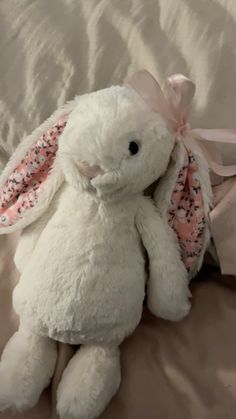 a white stuffed rabbit sitting on top of a bed