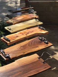 several wooden boards are lined up in a row on a table outside near some bushes