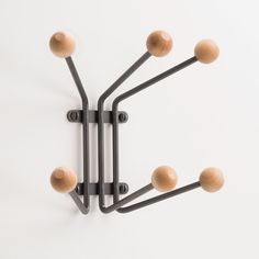 a wall mounted light fixture with six wooden balls on it's arm and four black metal arms