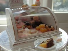 a miniature display case with pastries in it on a table next to a window