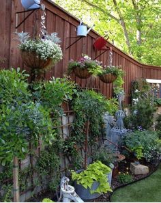 an outdoor garden with lots of plants growing on the wall and hanging from it's sides