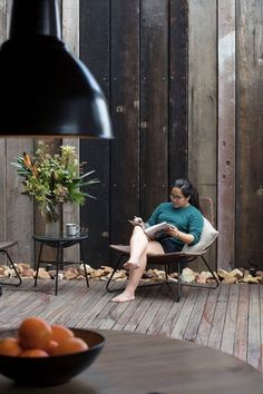 a woman sitting in a chair on top of a wooden deck