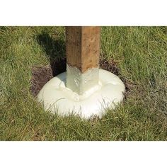 a wooden post sticking out of the ground next to a white object in some grass