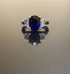 Dekara Designs Collection Metal- 90% Platinum, 10% Iridium. Stones- 1 Natural Untreated 3.88 Carat Oval Cut Ceylon Blue Sapphire. 2 Moon Cut Diamonds, F-G Color VS1 Clarity 0.77 total carats This ring is a size 6, but could be sized up or down a few sizes. This ring could be made in your specific size within 5-10 business days. Could take a little more time due to the ceylon sapphire being a rare stone. The sapphire may be a bit smaller or bigger. We can make the same design in a smaller or bigg Blue Sapphire Three Stone Ring With Diamonds, Classic Blue Sapphire Ring With Round Cut, Fine Jewelry Blue Three Stone Jewelry, Blue Lab-created Sapphire Promise Jewelry, Blue Lab-created Sapphire Jewelry For Promise, Blue Sapphire Diamond Ring With Center Stone, Blue Three Stone Round Cut Diamond Ring, Oval Blue Diamond Ring With Accent Stones, Classic Blue Rings With Lab-created Sapphire