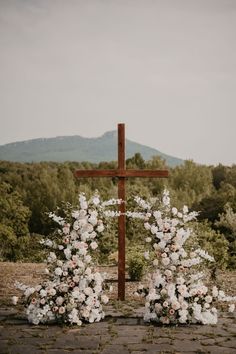 a cross and flowers on the ground in front of trees