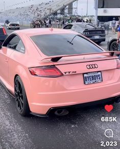 the back end of an audi car parked in a parking lot with people standing around